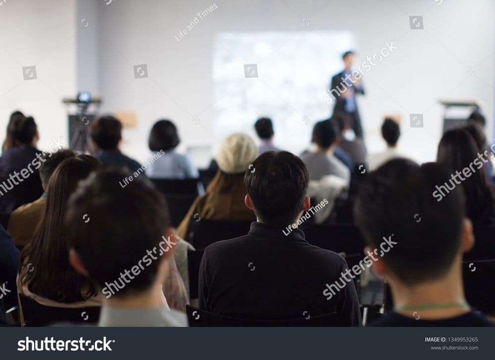 stock-photo-conference-photo-with-audience-business-crowd-and-executive-speaker-on-stage-presenter-giving-1349953265.jpg